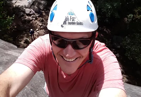 Man smiling while climbing Looking Glass Rock.